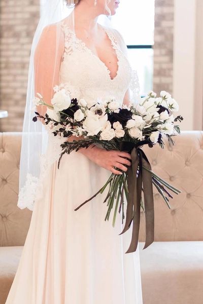 bride holding bouquet of white and black flowers