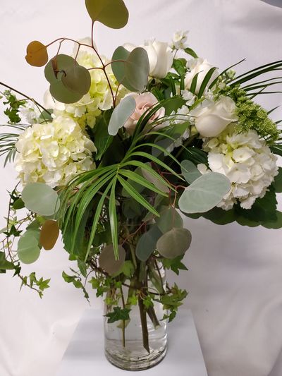 Elegant white hydrangeas floral arrangement in clear glass vase.