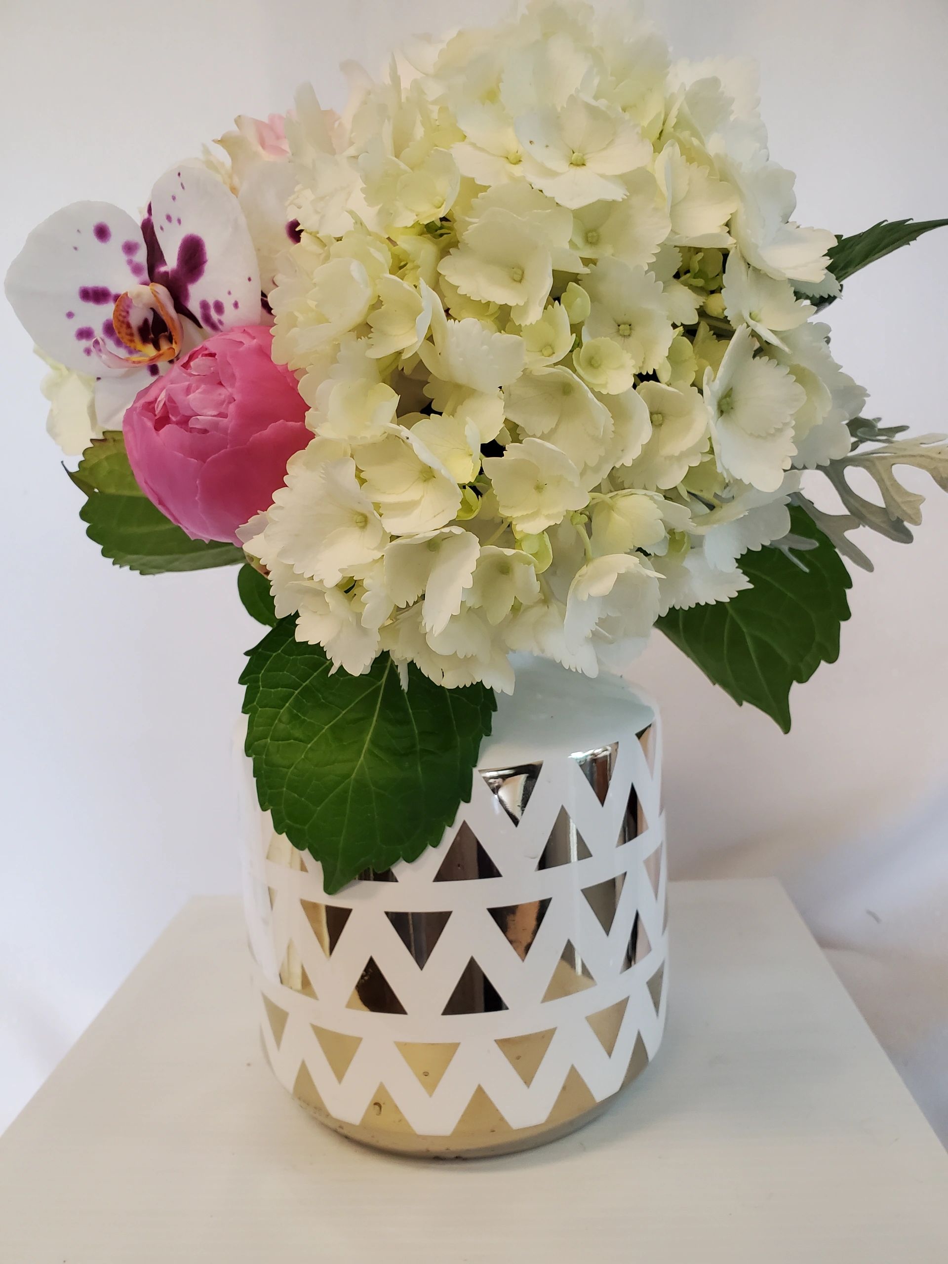 white hydrangeas, white orchids floral arrangement in an elegant vase.
