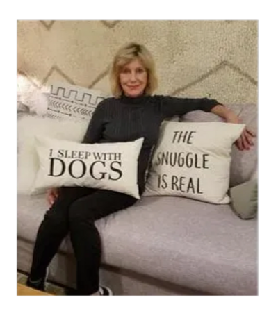 Woman sitting on a couch holding pillows with dog-related quotes.