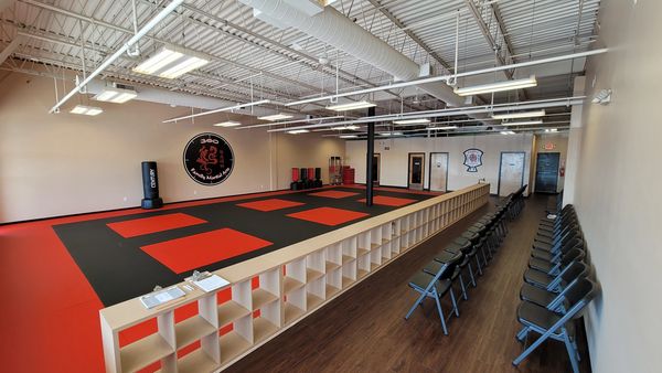 Spacious martial arts training area with padded flooring and seating.