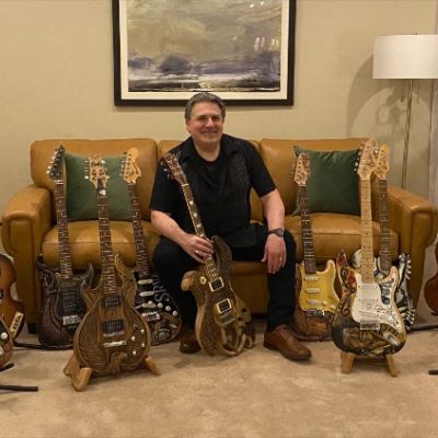 Man sitting surrounded by artistic electric guitars.