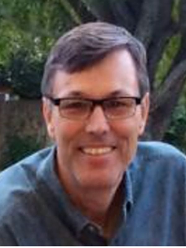 Smiling man wearing glasses outdoors.