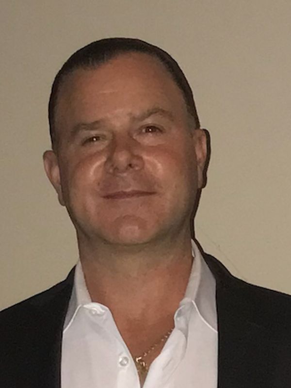 Smiling man in a dimly lit room.