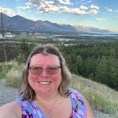 Woman smiling with mountainous landscape in the background.