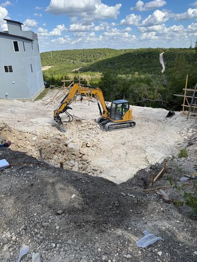 Excavator working on rocky terrain brining lot to foundation ready grade after the lot was cleared