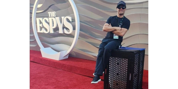 A man sitting on the red carpet with his arms crossed.