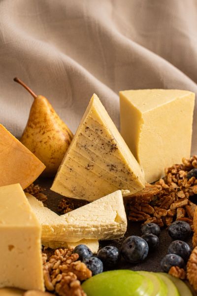 Assorted cheese wedges with pear, blueberries, walnuts, and apple slices.
