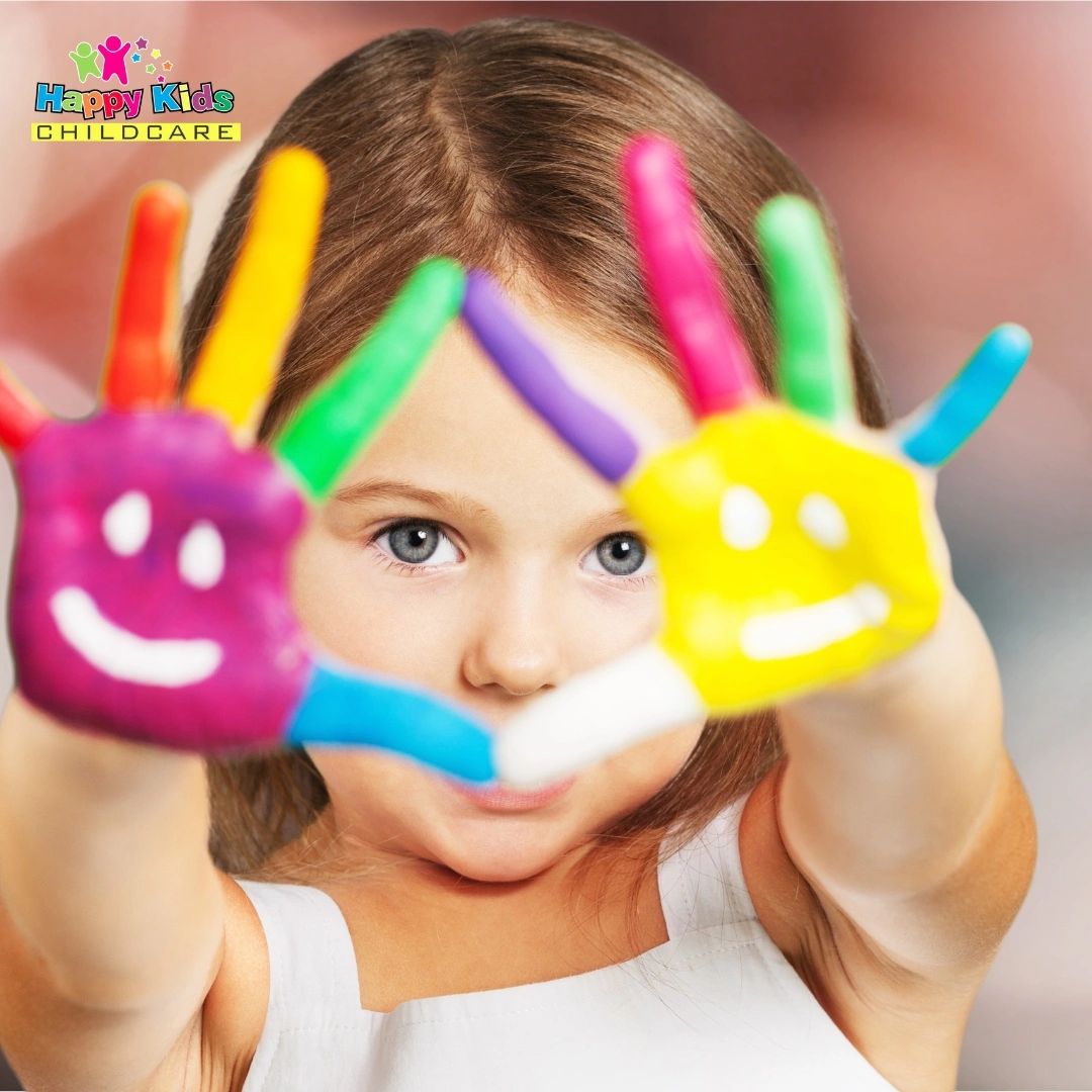 Child with painted colorful hands and smiley faces showing joy.