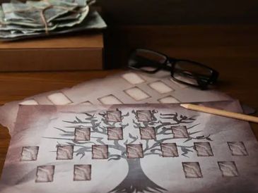 A family tree drawing with photos and glasses on a desk.