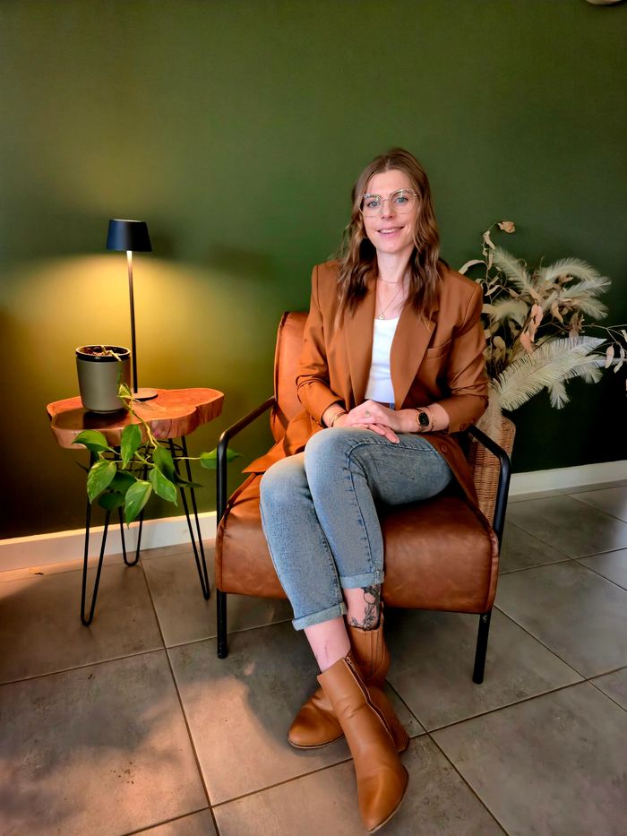 therapist sitting on a faux brown leather armchair smiling, 