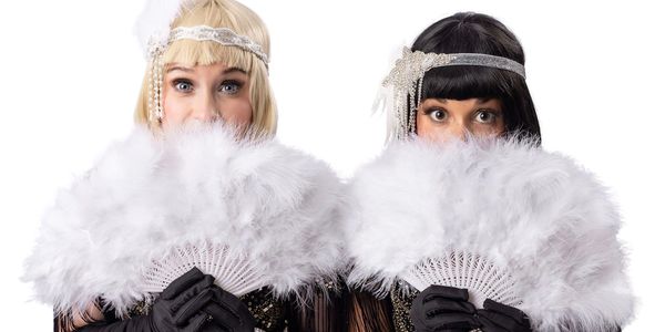 Two women in vintage attire hiding behind white feather fans.