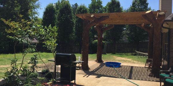 A pergola with Stonemaker® custom concrete trees and and extended patio, landscape & other features.