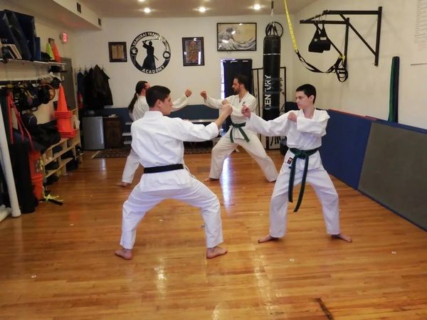 A small group of four karate students, wearing different colored belts, practicing in a dojo