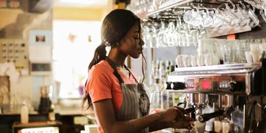 Barista preparing coffee using an espresso machine in a cozy café.