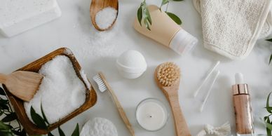 Flat lay of natural skincare and spa essentials with wooden and white accessories.