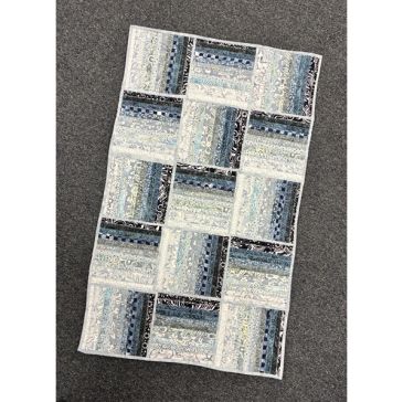 Quilt with various blue and gray patterned fabric blocks.