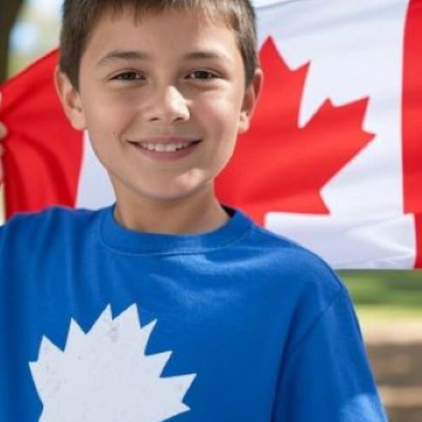 Smiling boy wearing a blue shirt with a white maple leaf, holding a Canadian flag.
