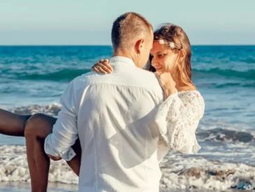 A couple shares a romantic moment by the ocean shore.