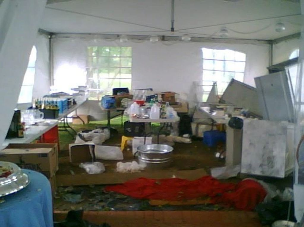 a catering kitchen under a tent, with hotboxes knocked over and mud everywhere