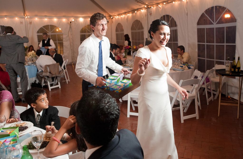 bride and groom smiling as they distribute party favors among their guests