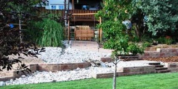 A landscaped backyard with a swing, stone pathway, and green lawn.