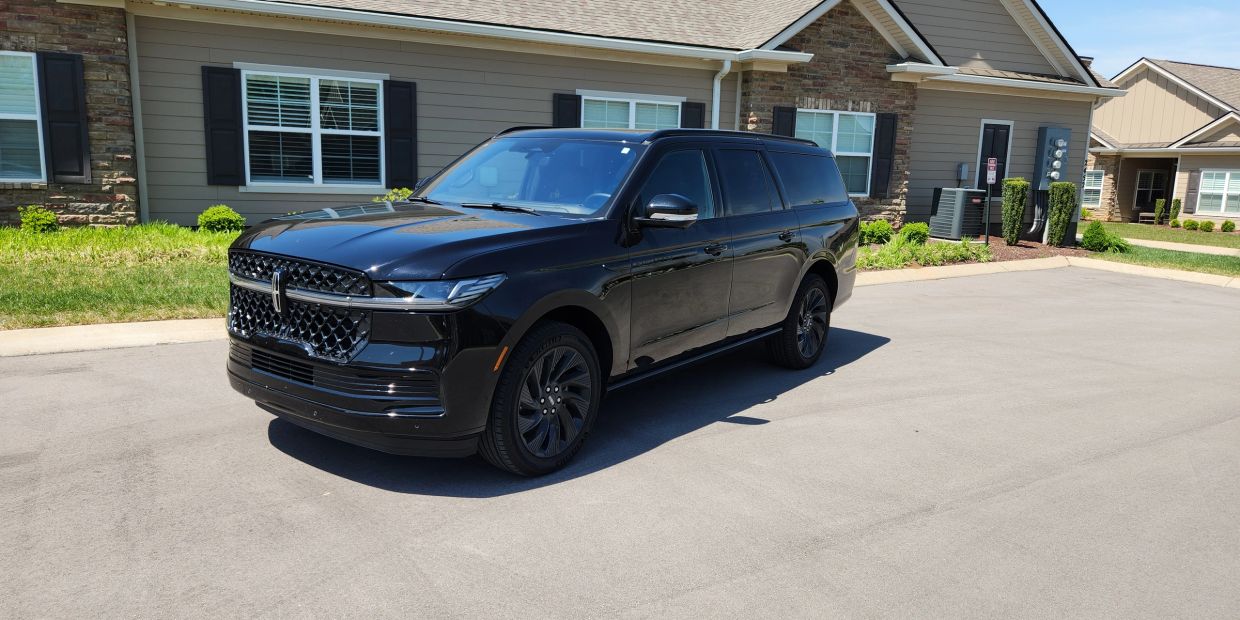 A sleek black SUV parked on a residential street on a sunny day.
