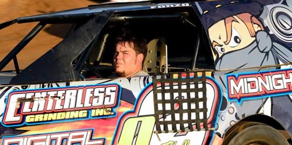 A man driving a colorful race car with sponsor logos.
