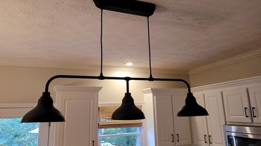 Black industrial-style three-light fixture hangs in a modern kitchen.