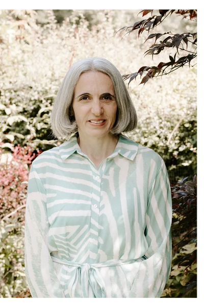 Middle-aged woman with gray bob haircut in patterned shirt standing outdoors.