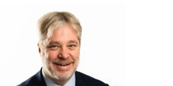 Smiling middle-aged man in suit and tie against white background.