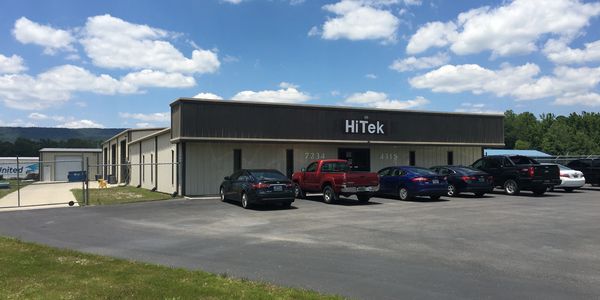 HiTek building with parked cars under a sunny sky.