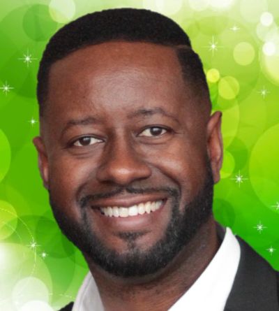 Smiling man in a suit with a green bokeh background.