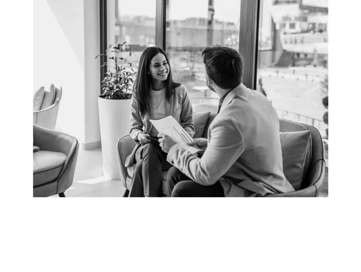 Two colleagues discussing work over charts in a bright office.