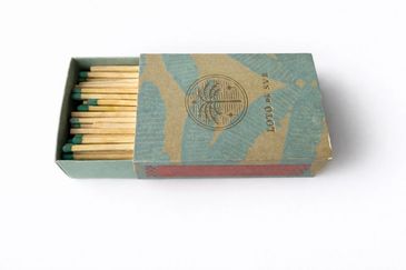 Open box of wooden matches with green tips.