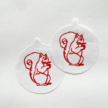 Two circular coffee stencils with red squirrel designs.
