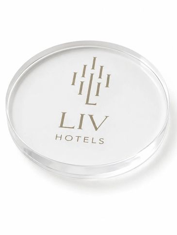 Clear round coaster with LIV Hotels logo in gold lettering.