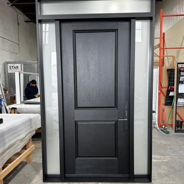 A modern black door with frosted glass panels on each side in a workshop.