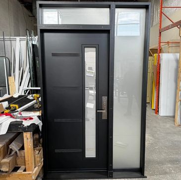 Modern black door with a vertical glass panel and side window in a workshop.