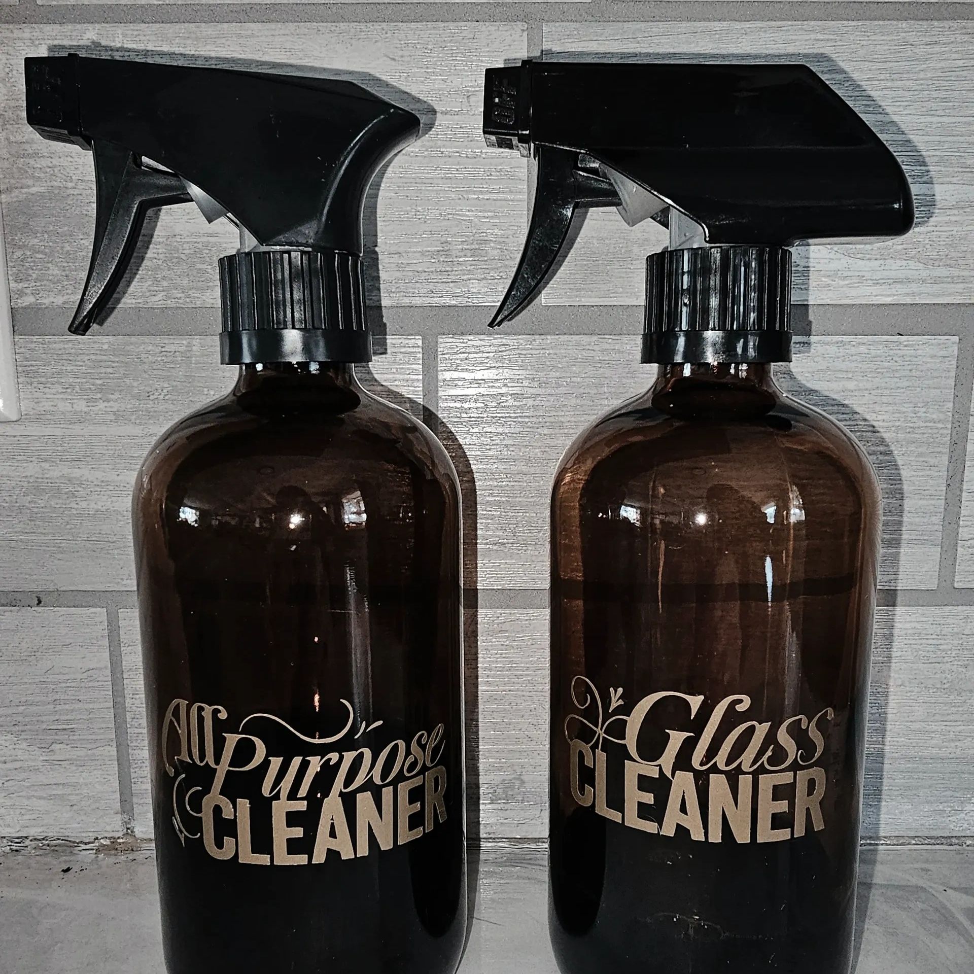 Two brown spray bottles labeled All Purpose Cleaner and Glass Cleaner.