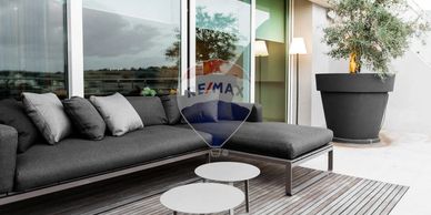 Modern outdoor patio with a gray sectional sofa and potted plant.