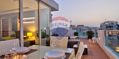 Modern rooftop terrace with dining setup at sunset.