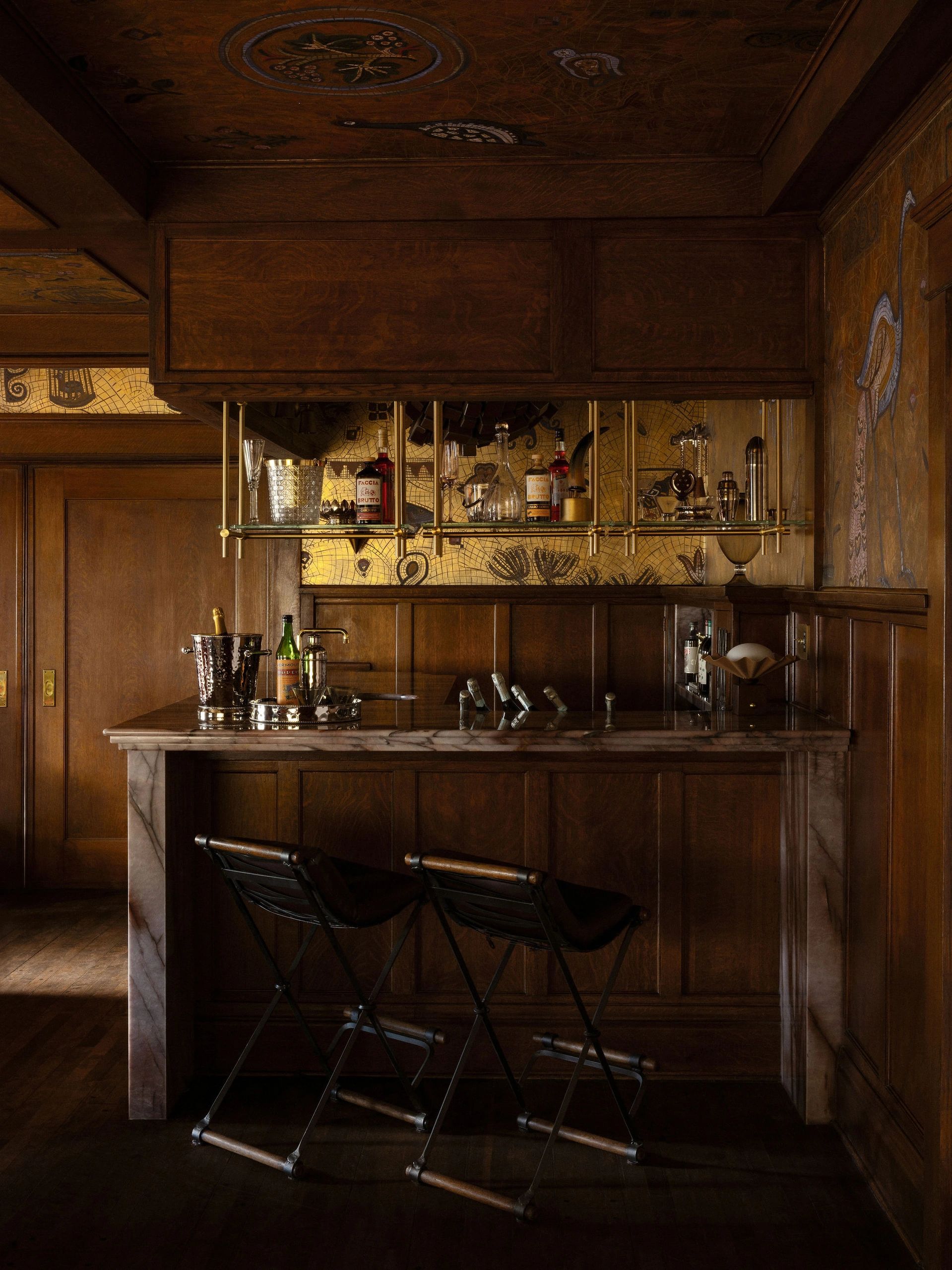 Elegant wooden bar area with vintage decor and two bar stools.