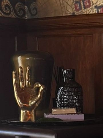Golden hand sculpture making an OK sign on a dark table.