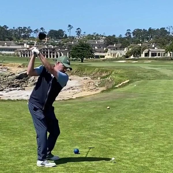 Golfer preparing to swing on a sunny coastal golf course.