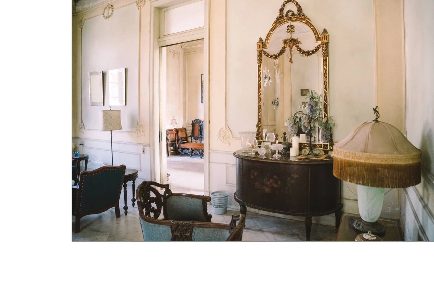 Elegant vintage living room with ornate furniture and a large gilded mirror.