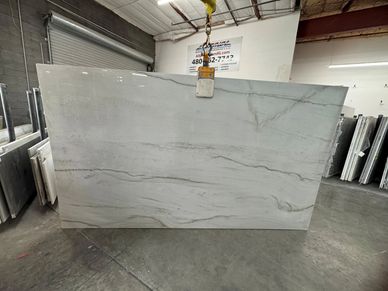 Large white marble slab with gray veining in a warehouse.