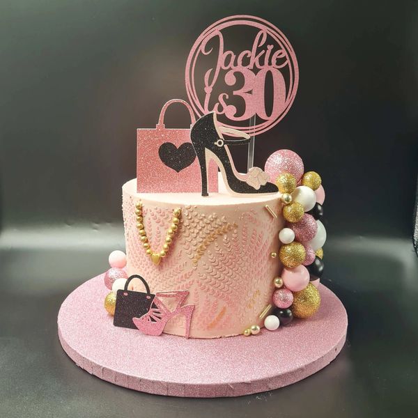 pink black and gold themed cake with balls high heels handbags and a stencil print