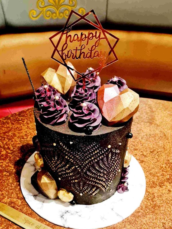 black cake with gold stencilling and geo hearts purple buttercream swirls