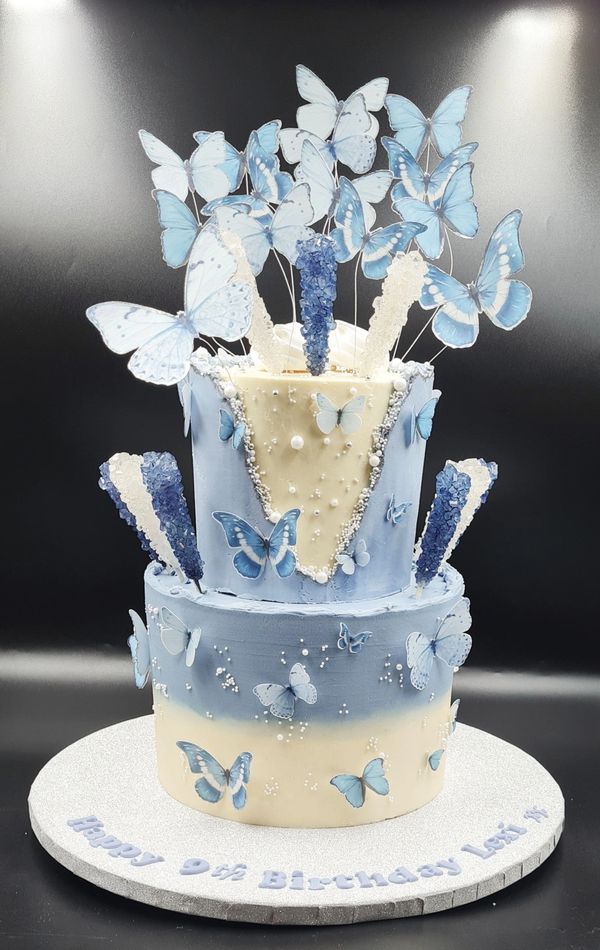 blue and white ombre 2 tier cake with blue butterflies and sugar sticks